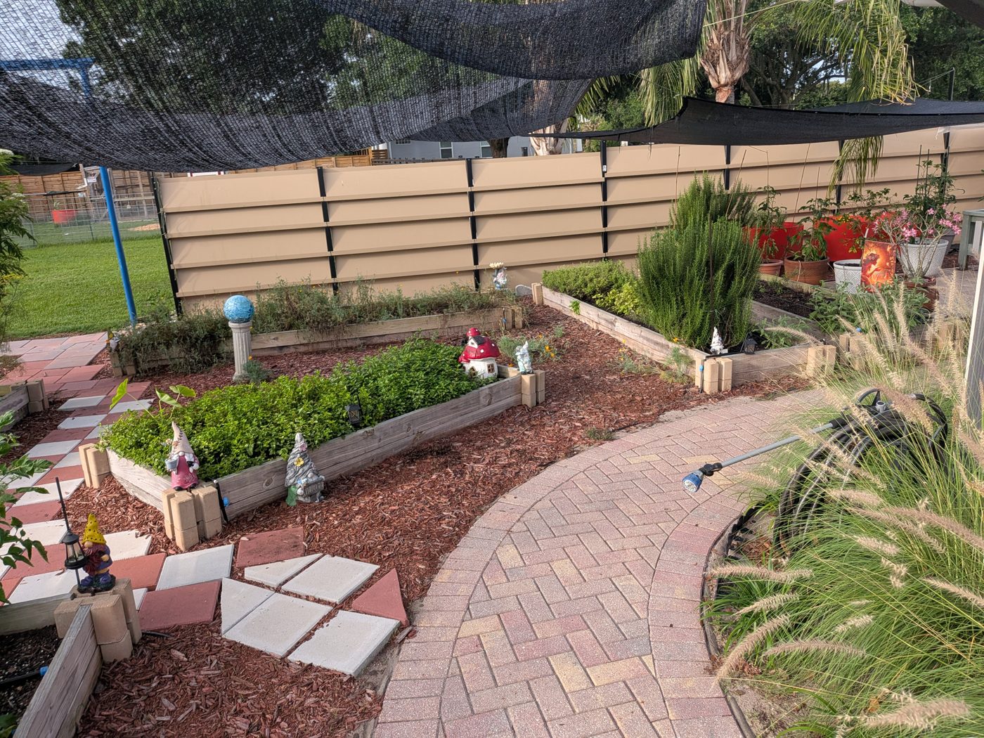 Curved brick path winding between raised herb garden beds
