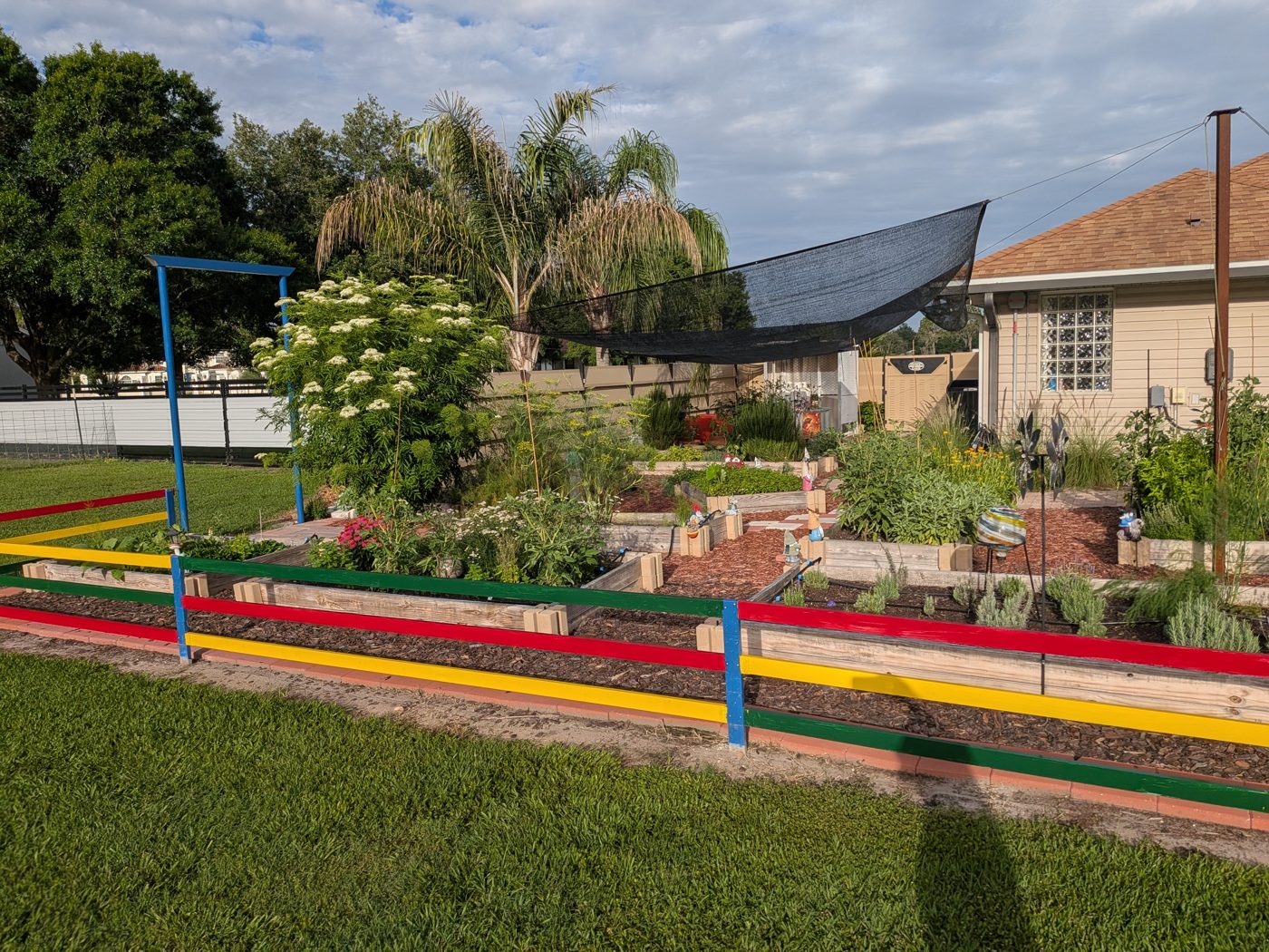 Wide view of Iola's herb garden in Plant City, Florida with raised beds and colorful painted rails